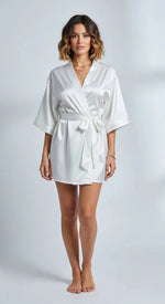 Robe curto de cetim branco feminino, com faixa na cintura e mangas amplas, brilho acetinado em luz suave.