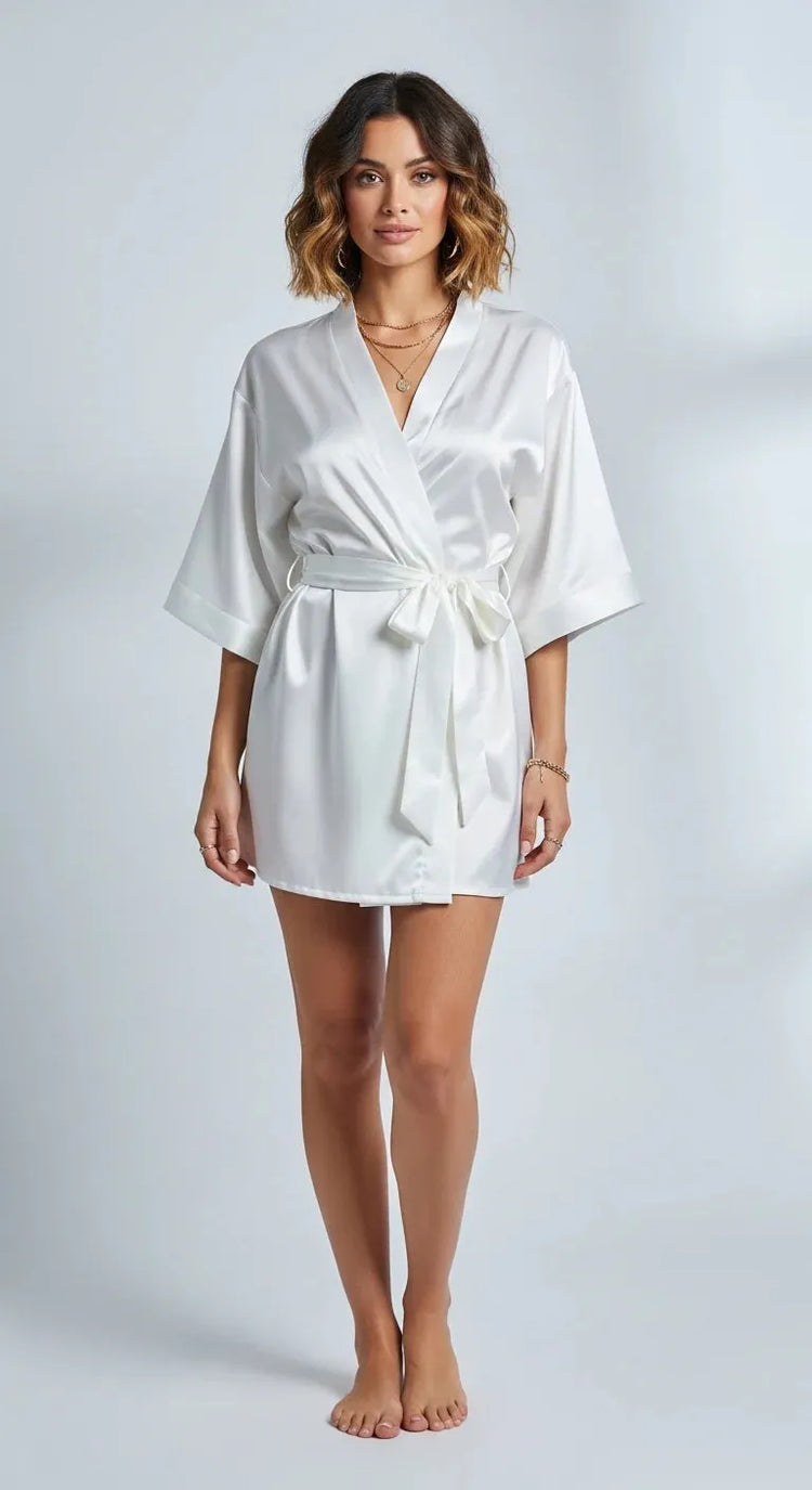 Robe curto de cetim branco feminino, com faixa na cintura e mangas amplas, brilho acetinado em luz suave.