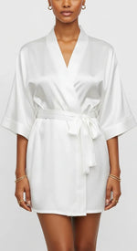Robe curto de cetim branco feminino, com faixa na cintura e mangas amplas, brilho acetinado em luz suave.