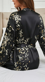 sentada na cama conjunto preto em cetim floral look noite confortável e sofisticado