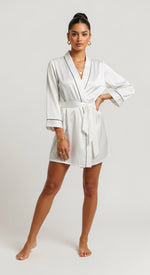 robe kimono curto branco em cetim pose frontal mão na cintura brilho acetinado e gola em V com vivo preto
