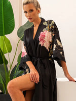 robe kimono preto floral sentado na cama laço central e caimento leve