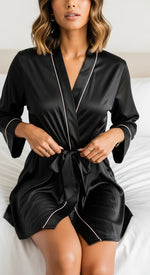 robe kimono curto preto de cetim sentada na cama tecido acetinado laço central e vivo rosa